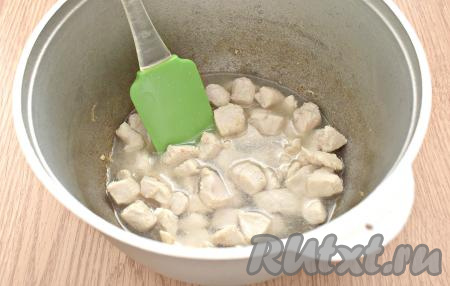 Убавляем нагрев плиты до чуть ниже среднего, аккуратно вливаем к куриным кусочкам 100 мл кипятка. Прикрываем казан крышкой и тушим курицу 10 минут.