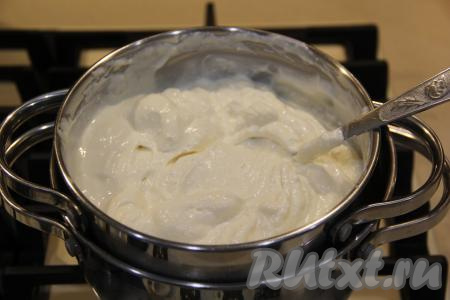 Готовить будем на водяной бане, для этого прежде всего нужно взять кастрюлю большего размера, чем кастрюля с творожной массой. Влить в эту большую кастрюлю воду, поставить на огонь и дождаться закипания воды. Затем уменьшить огонь до среднего и сверху установить кастрюлю с творожной массой. Дно кастрюли с творожной массой не должно касаться воды. Готовить при помешивании, примерно, 15 минут. Масса практически закипит. На этом этапе можно добавить какие-нибудь добавки (рубленную зелень или специи), я не добавляла. 