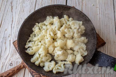 В сковороду налейте масло, нагрейте его, добавьте отваренную (или полностью размороженную) капусту.&nbsp;