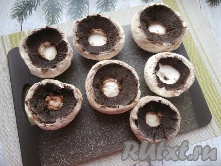 Удалить ножки у шампиньонов, внутреннюю часть шляпок посолить.