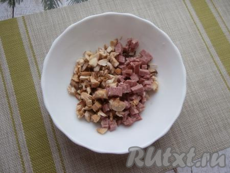 В отдельную миску мелко нарезать ножки шампиньонов, туда же нарезать на маленькие кубики колбасу.