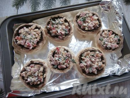 Шляпки разложить на противне, застеленном фольгой. Подготовленной начинкой нафаршировать шляпки шампиньонов.