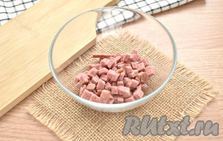 Нарезаем колбасу на мелкие кубики, перекладываем в миску.
