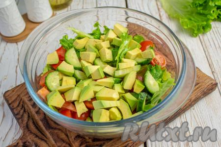 Авокадо разрежьте пополам, удалите косточку, затем очистите его от кожицы. Мякоть нарежьте на небольшие кубики и тоже добавьте в салатник.