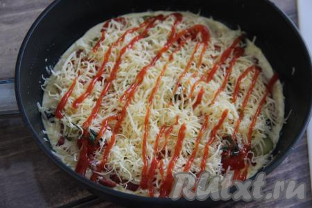 Присыпать пиццу натёртым сыром и нанести сеточку из кетчупа.