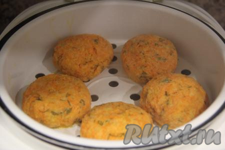 В основную чашу мультиварки влить воду, поддон с морковными котлетами поставить сверху, сразу закрыть крышку мультиварки и готовить на режиме "На пару" 30 минут.