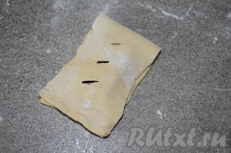 Частью теста с разрезами накрыть часть теста, на которой лежит долька шоколада, формируя слойку.