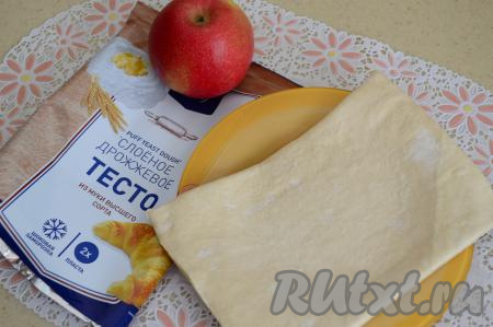 При комнатной температуре разморозить слоёное тесто (у меня тесто разморозилось минут за 30, но продолжительность разморозки зависит от температуры в помещении). Я готовила рогалики из пласта слоёного теста размером 14 см на 21 см.