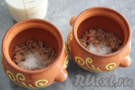Разделить промытую пшеничную крупу на две части и разложить по двум горшочкам объёмом по 400 мл. Добавить в каждый горшочек 1/4 чайной ложки соли и одну столовую ложку сахара.&nbsp;