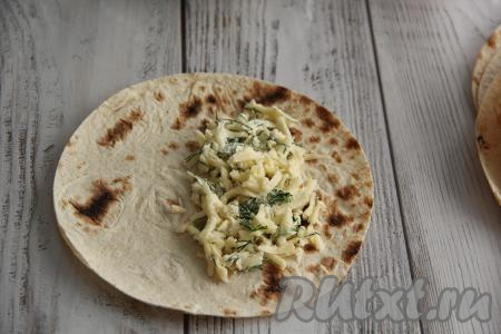 Из лаваша вырезать круги. Я вырезала острым ножом круги из лаваша, приложив тарелку диаметром 18 см. Лучше всего исходить из диаметра вашей сковороды, так как в дальнейшем мы будем жарить чебуреки на сковороде. У меня получилось 8 заготовок. Подготовленную начинку я тоже разделила на 8 частей. Выложить на половину каждого круга лаваша часть начинки, немного отступив от края лаваша (как на фото).