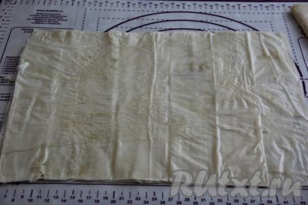 Полностью разморозившееся тесто фило достать из упаковки. У меня оно было свёрнуто в рулет, я развернула этот рулет и расправила тесто. Разделила расправленное тесто фило на 2, примерно, равные части. Затем одну часть теста убрать в пакет, чтобы оно не сохло. Вторую часть теста разделить&nbsp;на листы (у меня тесто состояло из шести листов). Каждый лист смазать растительным маслом и выложить смазанные листы друг на друга. Масла не жалеем, я смазывала руками.&nbsp;