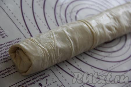 Подвернуть края теста с трёх сторон, слегка накрывая начинку, а затем, начиная со стороны с начинкой, свернуть тесто в рулет. Аналогично сформировать второй штрудель с яблоками, орехами и изюмом из теста фило.