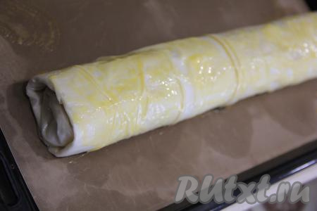 Два штруделя аккуратно переложить на противень, застеленный тефлоновым ковриком для выпечки (или пергаментной бумагой). Смазать верх теста взбитым желтком и поставить противень со штруделями в разогретую духовку.