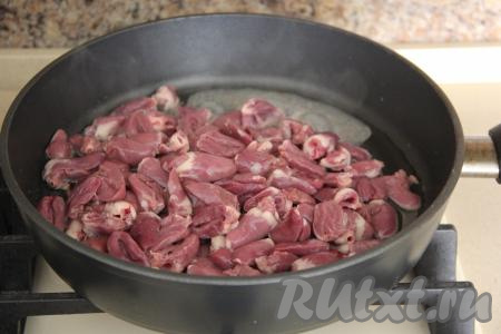 В сковороду влить масло и разогреть. Выложить в сковороду подготовленные куриные сердечки, обжарить их на сильном огне, помешивая, минут 7.