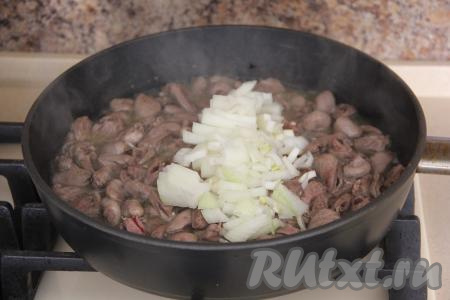 Лук мелко нарезать и добавить к сердечкам, обжаривать минут 5, помешивая, на среднем огне.
