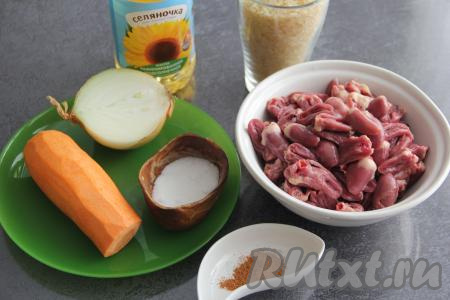 Подготовить продукты для приготовления куриных сердечек с рисом на сковороде. Лук и морковь почистить. Сердечки разрезать пополам, удалить крупные сосуды и промыть, убирая сгустки крови.