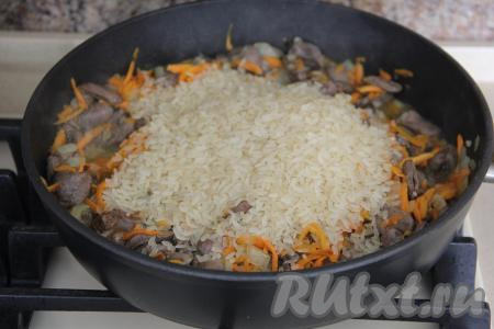 Всыпать в сковороду рис. Я использовала пропаренный рис. Если используете не пропаренный рис, то хорошо промойте его, дайте стечь воде, а затем добавьте в сковороду с куриными сердечками и овощами.&nbsp;