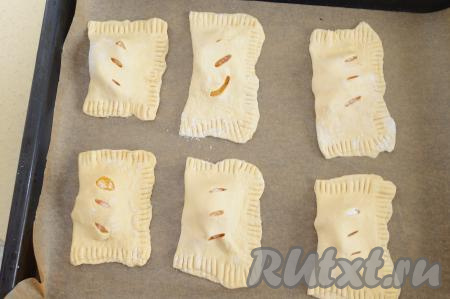 Сформированную слойку переложить на застеленный пекарской бумагой противень. Если не уверены в качестве бумаги, перед выкладываем слоек, смажьте её слегка растительным маслом, тогда выпечка не пристанет к пергаменту. Аналогично сформировать все слойки с апельсином и переложить на противень.