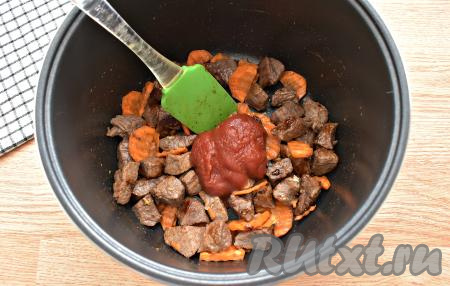 Затем в чашу мультиварки с говядиной и овощами выкладываем томатную пасту, перемешиваем и обжариваем ещё 2 минуты.