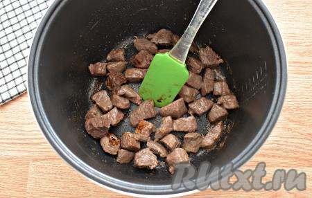 Вливаем 1 столовую ложку растительного масла в чашу мультиварки, сразу включаем программу «Жарка». Когда масло прогреется, перекладываем в чашу кусочки говядины. Периодически перемешивая, обжариваем мясные кусочки 10 минут. Мультиварку крышкой не накрываем.