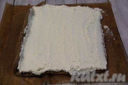 Развернуть корж, аккуратно снять тефлоновый коврик (или пергамент). Смазать поверхность коржа творожным кремом.