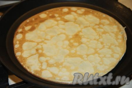 Сковороду раскалить, перед выпечкой первого блинчика можно смазать её немного растительным маслом. На подготовленную сковороду влить половник блинного теста, равномерно распределить. Выпекать блинчик до золотистости с двух сторон, затем переложить на тарелку. Перед выпечкой каждого блина блинное тесто следует перемешивать. Пожарить один за другим все блины.