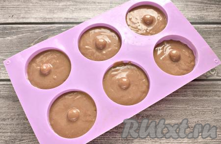Шоколадное тесто выкладываем ложкой в силиконовые формочки, заполняя их на 2/3 объёма, так как тесто поднимется в процессе выпечки в духовке.
