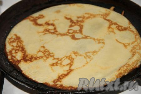 Сковороду (у меня сковорода диаметром 20 сантиметров) хорошо разогреть. Я смазываю сковороду маслом только перед жаркого первого блинчика. На раскалённую сковородку влить половник теста, распределить его равномерно и жарить блин до подрумянивания с двух сторон на среднем огне, затем переложить на тарелку. Пожарить из оставшегося теста один за другим все блинчики, складывая их на тарелку. Для формирования пирога понадобится 5 блинов, их нужно полностью остудить.