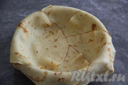 Керамическую или жаропрочную форму (у меня форма диаметром 20 сантиметров) слегка смазать маслом, затем выстелить блинами внахлёст (мне потребовалось 5 блинов), оставляя края блинчиков свисать с краёв формы.