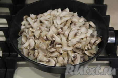 Шампиньоны промыть водой. 3-4 шампиньона оставить для украшения, оставшиеся грибочки нарезать на пластинки. Нарезанные шампиньоны выложить к обжаренному луку.