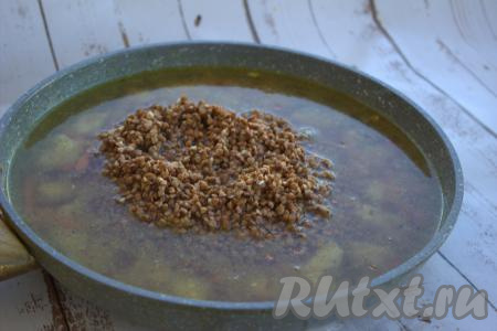 В сковороду с курицей и овощами выложить промытую гречку, влить 500 мл тёплой воды, разровнять гречку.