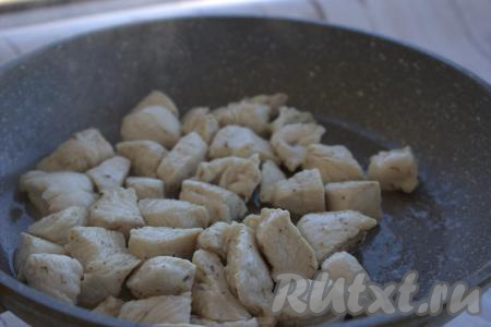 В глубокую сковороду (можно готовить и в казане) влить растительное масло, разогреть его и выложить кусочки куриного филе, обжарить мясо на достаточно сильном огне, иногда помешивая, до подрумянивания со всех сторон (на это потребуется минуты 2-3), немного поперчить.