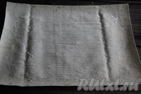 Каждый лист лаваша смазать сметаной, оставляя края чистыми.