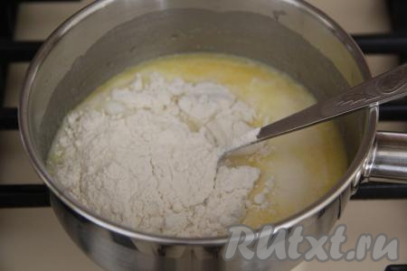 Снять с огня и сразу в смесь молока и масла всыпать 3 столовые ложки муки от общей массы. Перемешать быстро и тщательно массу ложкой, заваривая муку.
