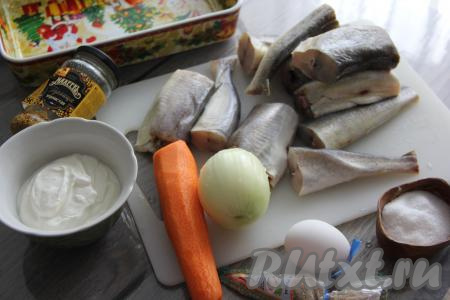 Подготовить продукты для приготовления наваги в сметане в духовке.  Лук и морковь почистить. Разморозить навагу при комнатной температуре (или на нижней полке холодильника). Если у вас непотрошёная тушка, тогда отрежьте плавники, хвосты, головы, удалите из брюшка внутренности с чёрной плёночкой, счистите, если есть, чешую, а затем хорошо промойте рыбку водой. Я взяла 1 килограмм уже потрошёной рыбы. Нарезать навагу на крупные порционные кусочки.