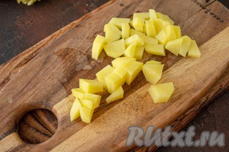 В кастрюлю налейте 1,5 литра воды, доведите её до кипения. Очищенные картошины нарежьте на мелкие кубики, переложите в кипящую воду и варите после закипания 10-12 минут (до полуготовности) на небольшом огне.
