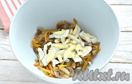 Перекладываем остывшие шампиньоны с морковью и луком в достаточно объёмную миску, добавляем нарезанные яйца. 