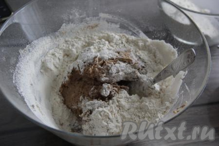 Всыпать разрыхлитель и часть просеянной муки, перемешать пряничное тесто ложкой.
