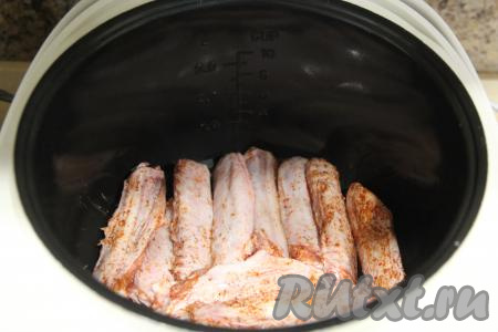 В чашу мультиварки влить растительное масло, затем выложить утиные крылья, стараясь располагать их в один слой.