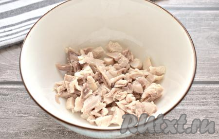 Куриное мясо (это может быть грудка, бедро или окорочок) кладём в кастрюлю, заливаем водой, солим, доводим на достаточно сильном огне до кипения, а затем, уменьшив огонь, варим минут 25-30. Достаём варёное мясо, после остывания отделяем от костей. 200 грамм куриного мяса нарезаем на небольшие кубики, выкладываем в миску.