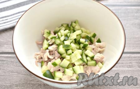 Свежий огурец моем, отрезаем концы, а затем нарезаем огурчик на небольшие кубики и добавляем в миску с куриным мясом.