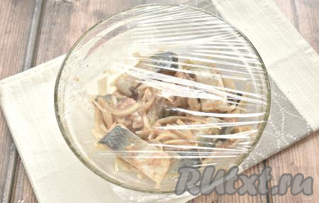 Миску с кусочками сельди с томатной пастой, луком и специями затягиваем пищевой плёнкой и убираем в прохладное место (можно поставить в холодильник) мариноваться на 4 часа. В течение этого времени кусочки селёдки пару раз перемешиваем.