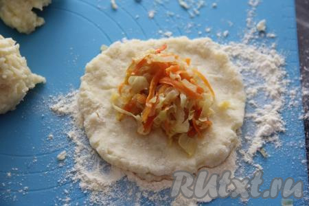 Разделить картофельную массу на 7 частей. Каждую часть картофельной массы на присыпанной мукой поверхности размять в лепёшку. Остывшую капустную начинку разделить на 7 частей. В центр каждой лепёшки выложить часть капустой начинки. 