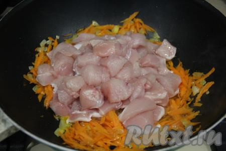 К обжаренным овощам выложить куриное филе, нарезанное на кубики среднего размера.