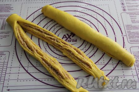 Скрутить каждый пласт теста в плотный рулет, начиная с широкой стороны. Разрезать вначале один рулет вдоль, не дорезая 5 сантиметров до конца, и свернуть в косу. Аналогично сформировать косу из второго рулета. У нас получатся 2 косы.