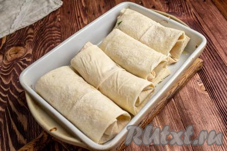 Таким образом подготовьте все заготовки из лаваша с куриным филе. Выложите их в подходящую посуду для запекания.