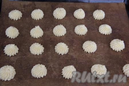 Переложить тесто в кулинарный мешок с фигурной насадкой и отсадить печенье на противень, застеленный тефлоновым ковриком (или бумагой для выпечки) на расстоянии друг от друга. Можно просто выложить печенье столовой ложкой. Во время выпекания печенье немного расплывётся.