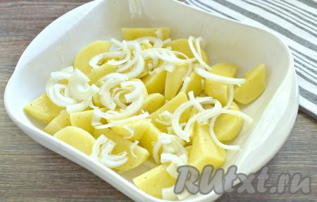 Картошку перекладываем в форму для запекания. Луковицу очищаем, нарезаем на достаточно тонкие полукольца и раскладываем поверх картофеля.