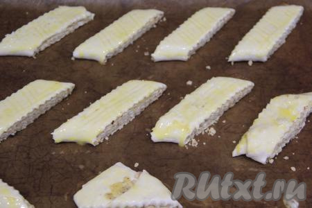 Выложить заготовки на противень, застеленный ковриком для выпекания (или пергаментом). Смазать сверху заготовки гаты взбитым желтком. Поставить противень в разогретую до 180 градусов духовку.