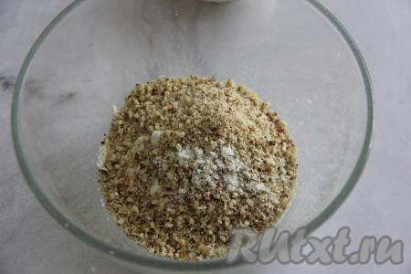 Орехи измельчить в крошку, переложить в объёмную миску, добавить сахар, муку и ванилин, перемешать.&nbsp;